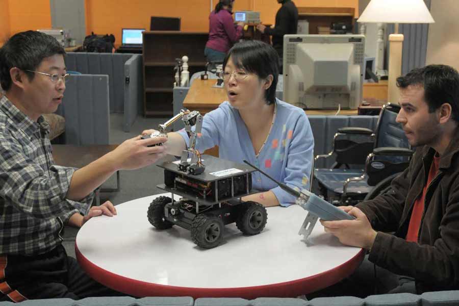Three computer engineering students with a remote-control robat