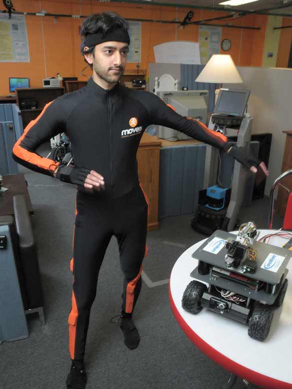 Computer science student controlling a robot the bodily movement measured inn his suit.