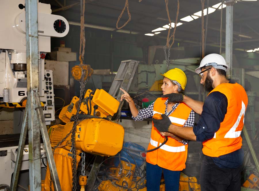 Two engineers inspect a machine in an industrial environment