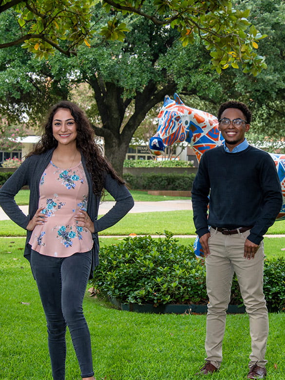 Student stand in front of a spirit horse on UTA campus. 
