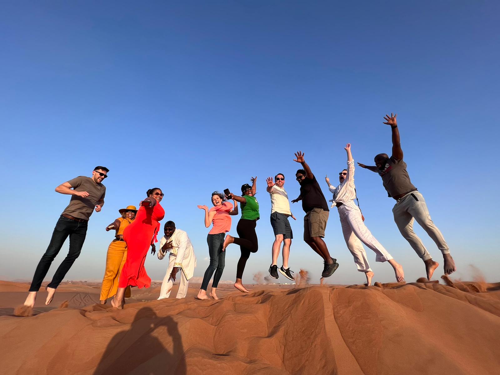 UTA Executive MBA Cohort jumping on a sand dune in UAE during international trip