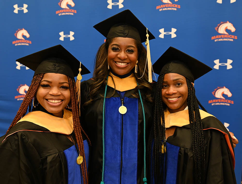 three graduates smiling at commencement
