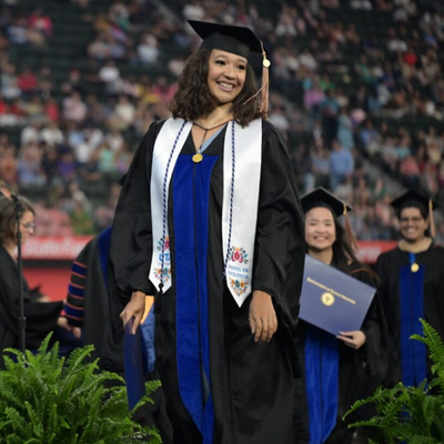 photograph of a woman at graduation with a white stole and graduation cap
