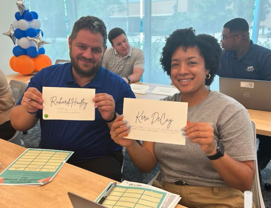 two people holding up papers with their names