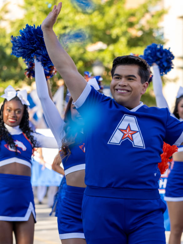 A cheerleader waves to the crowd
