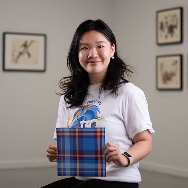 student rachel chen holding a print of her tartan plaid design