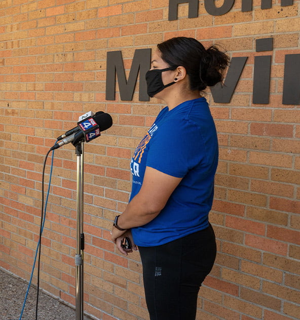 woman in mask speaking into a microphone