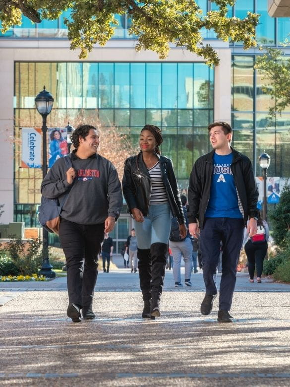 three UTA students walk near the SEIR building on campus