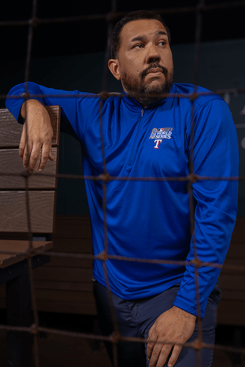 A man in a blue pullover standing in a baseball dugout