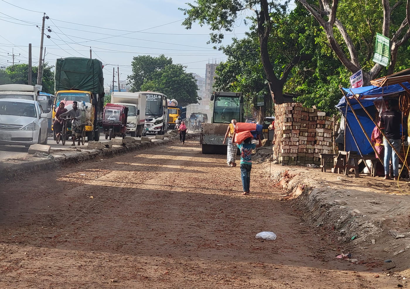 construction vehicles clear a path for a plastic road in Bangladesh