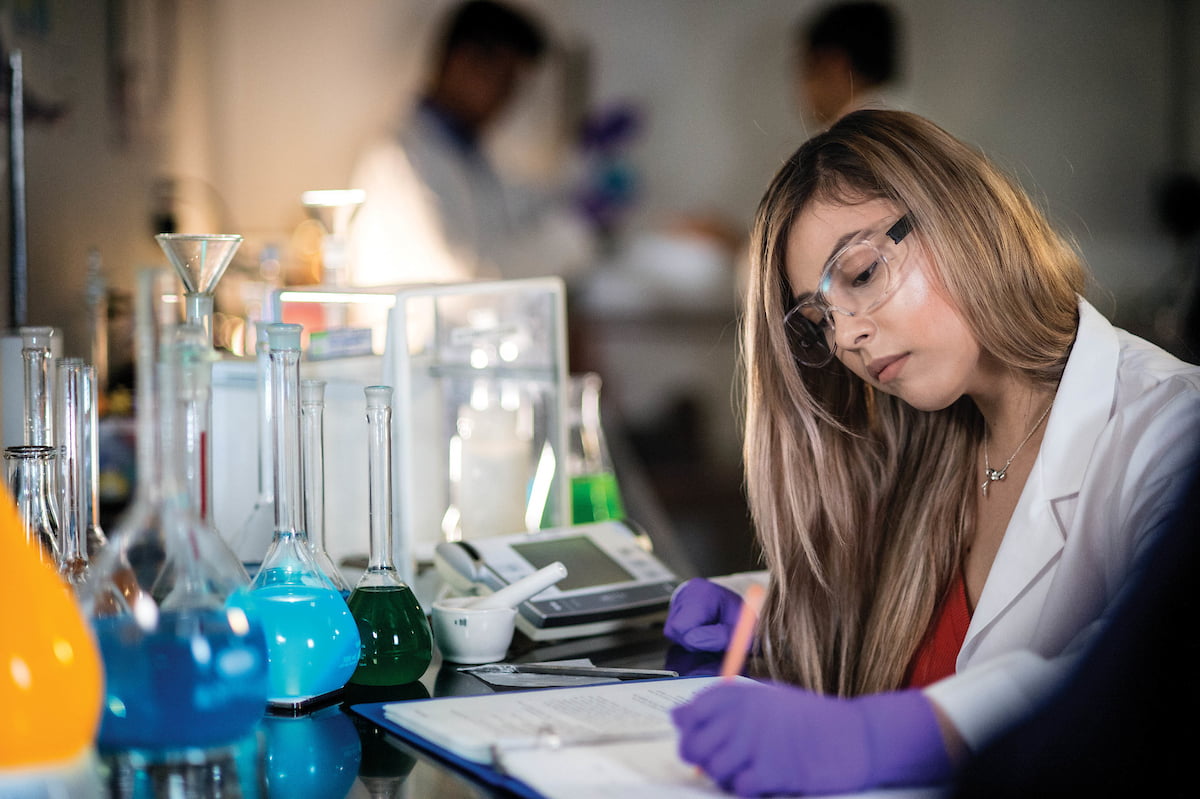 Student taking notes in research lab" _languageinserted="true