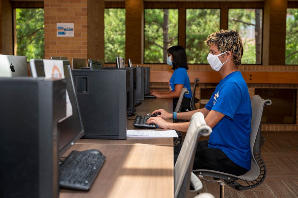 UTA students wearing face coverings in a socially distant computer lab