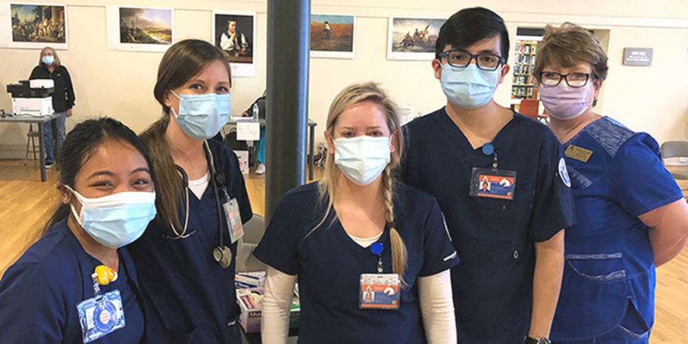 A group of nursing students pose for a photo at a rural vaccination clinic." _languageinserted="true