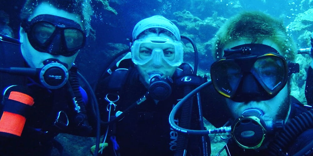 From left, Bradford Dimos, Laura Mydlarz and Nicholas MacKnight diving in Roatan, Honduras. 