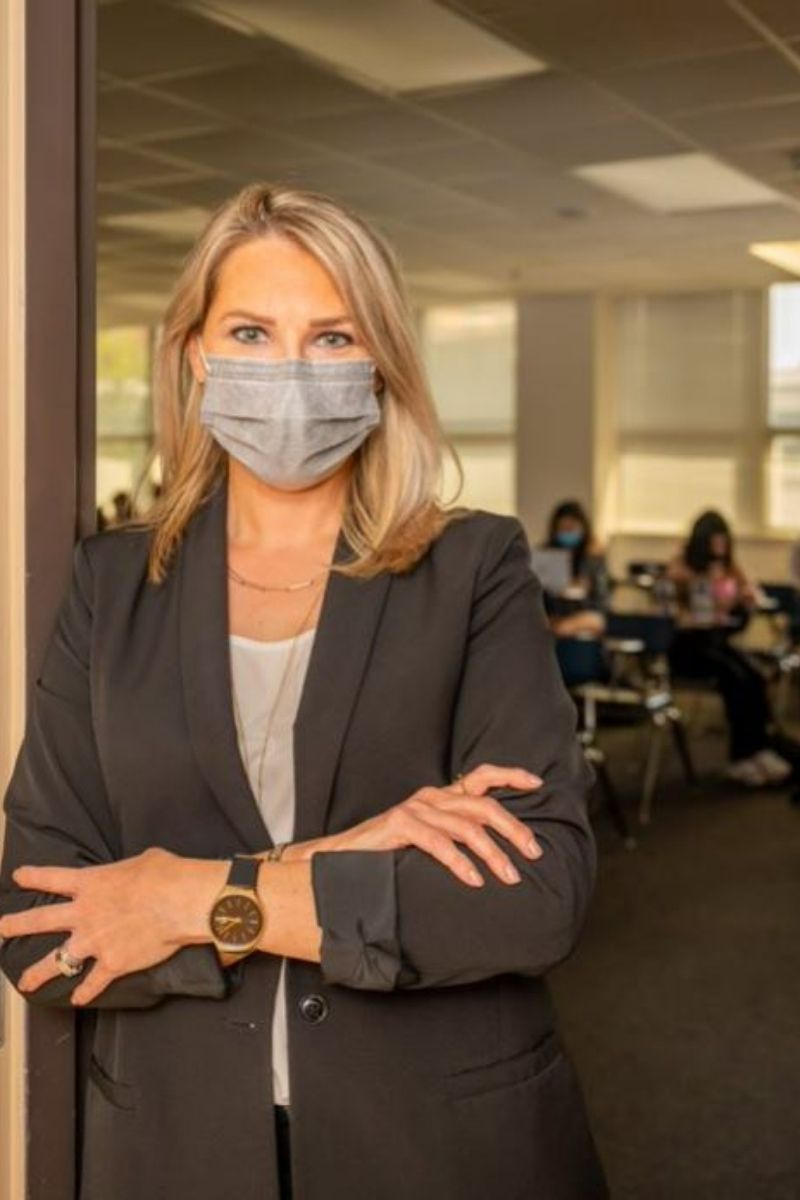 Erin Carlson poses in front of classroom with mask on." _languageinserted="true