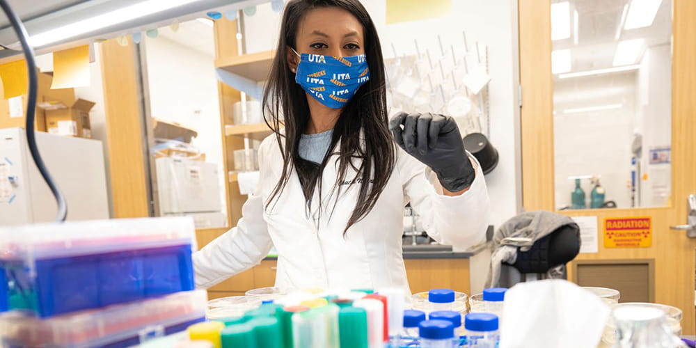A female researcher examines items in a lab." _languageinserted="true
