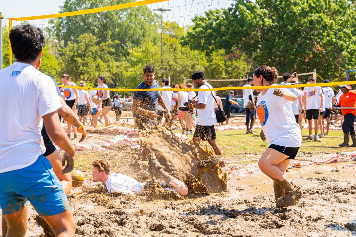 UTA students play the game of oozeball , volleyball played in mud. A player dives into the mud, causing it to splash all around." _languageinserted="true