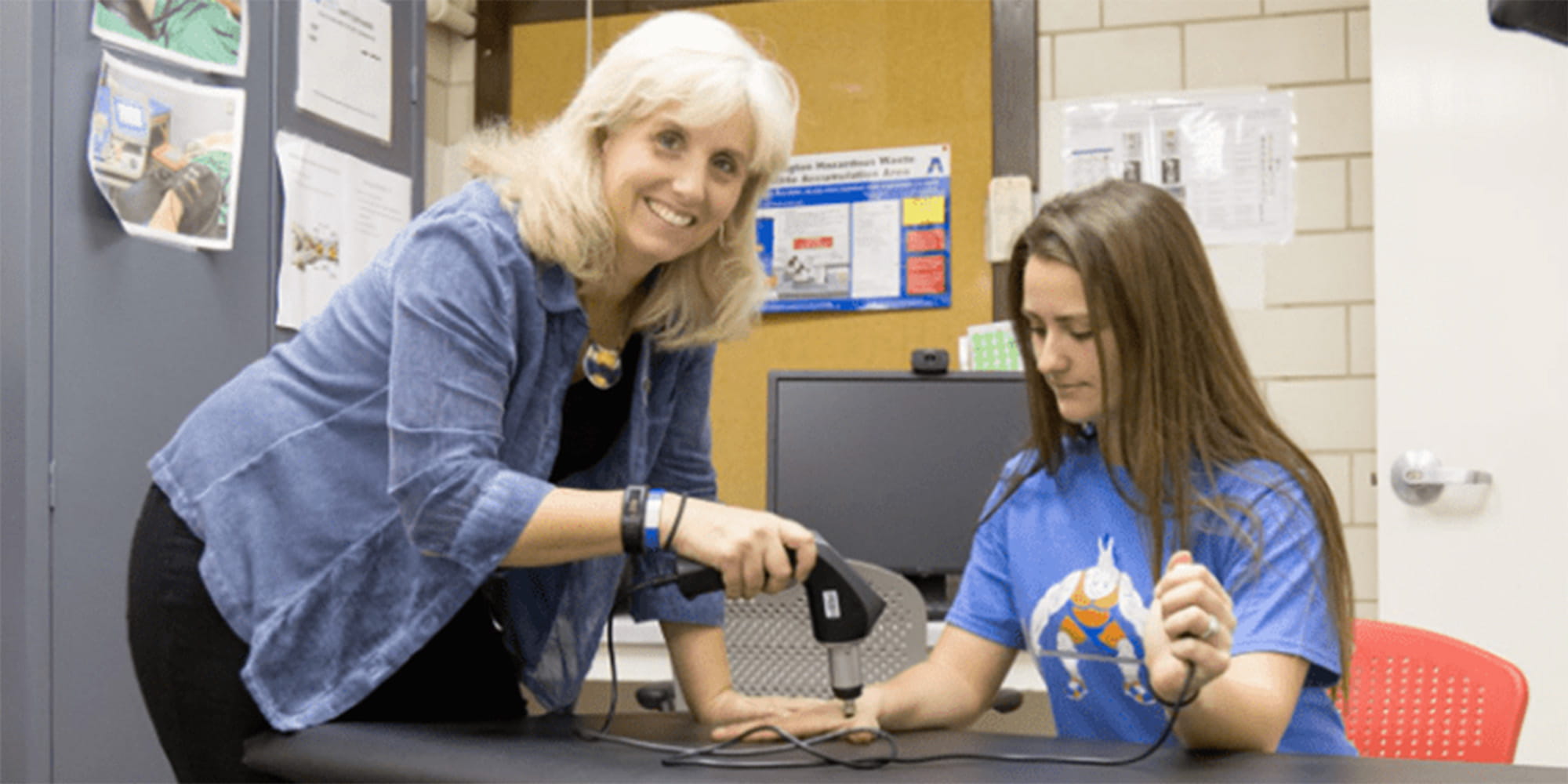 Cindy Trowbridge demonstrates an athletic training technique on a student volunteer." _languageinserted="true