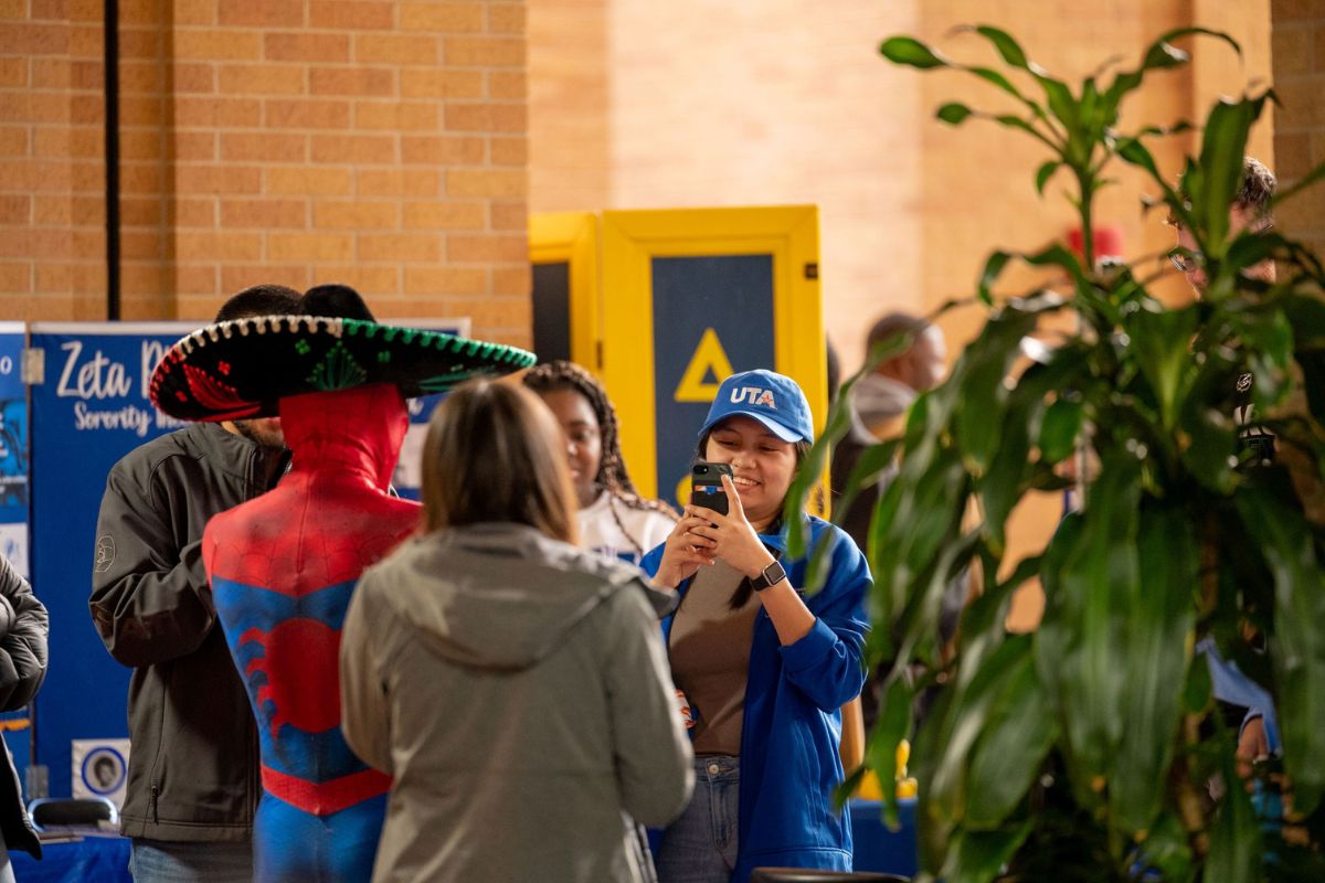 A UTA student takes a photo of a group of other students