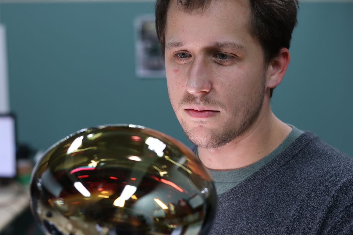 Benjamin Smithers stares at an instrument with a reflective surface in the laboratory at Chiba University." _languageinserted="true