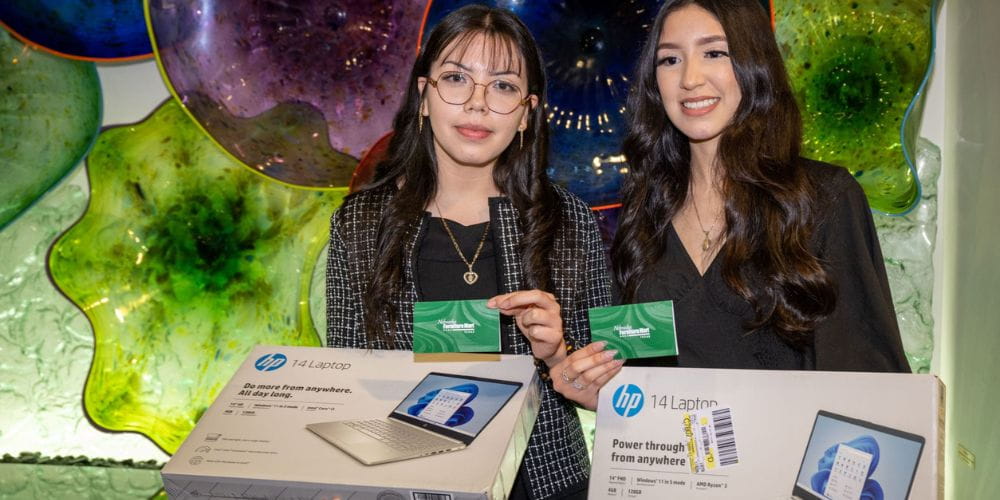 Maria Belen Cruz Garay and Belinda Alonso holding a laptop and giftcard