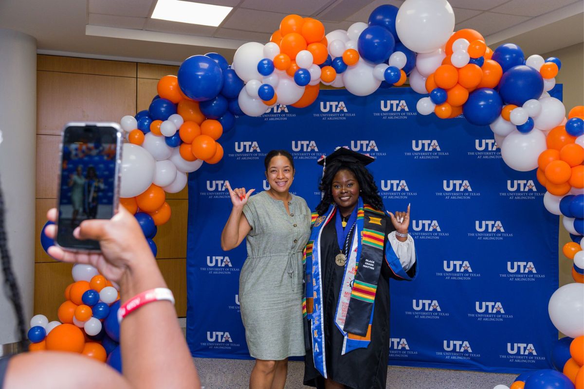 UTA grad and family member doing mavs up sign