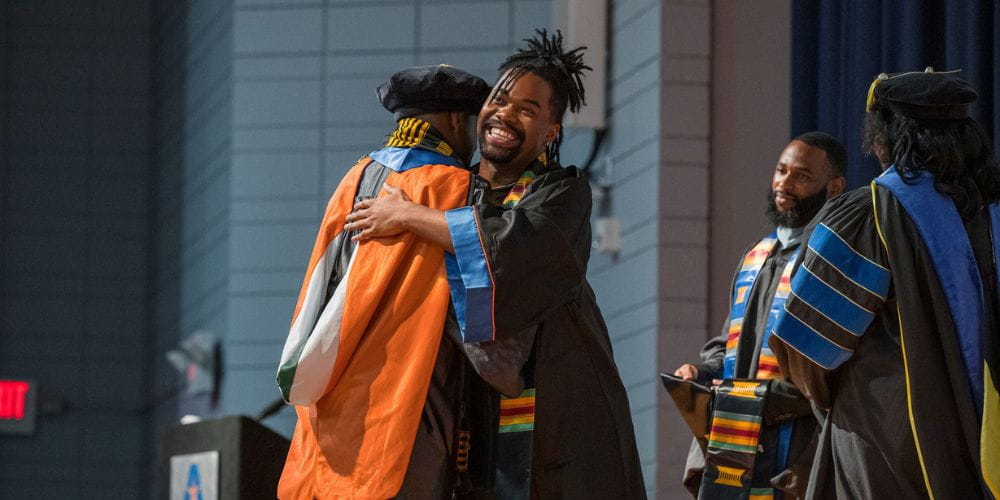 UTA grad hugs faculty member at EOBE celebration