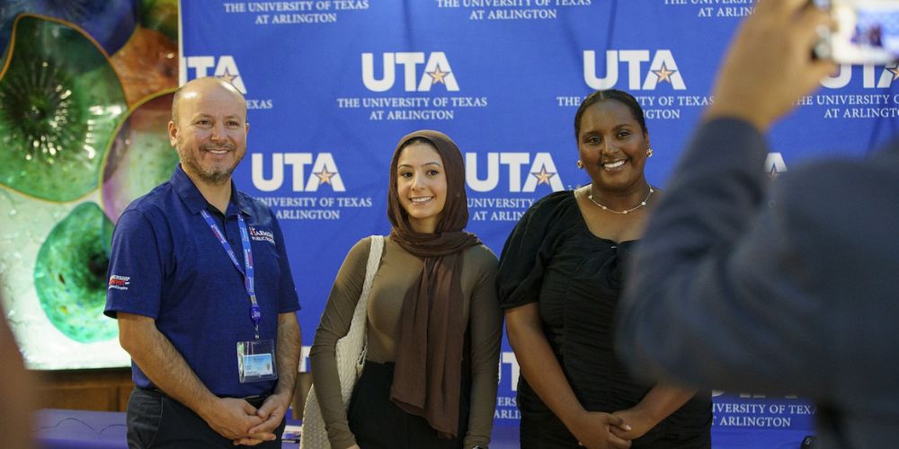 Harmony Public Schools representative poses for a photo with UTA students.