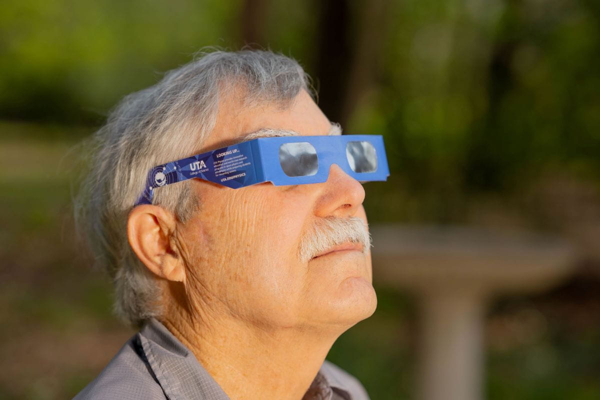 Photo of UTA alum Bob Bedell wearing UTA branded solar eclipse glasses
