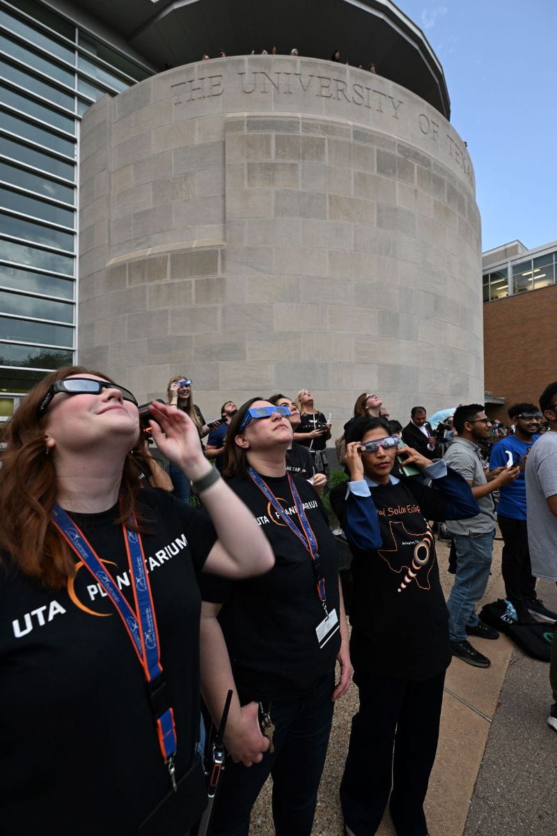 Photo outside UTA Planetarium of people looking up with eclipse glasses