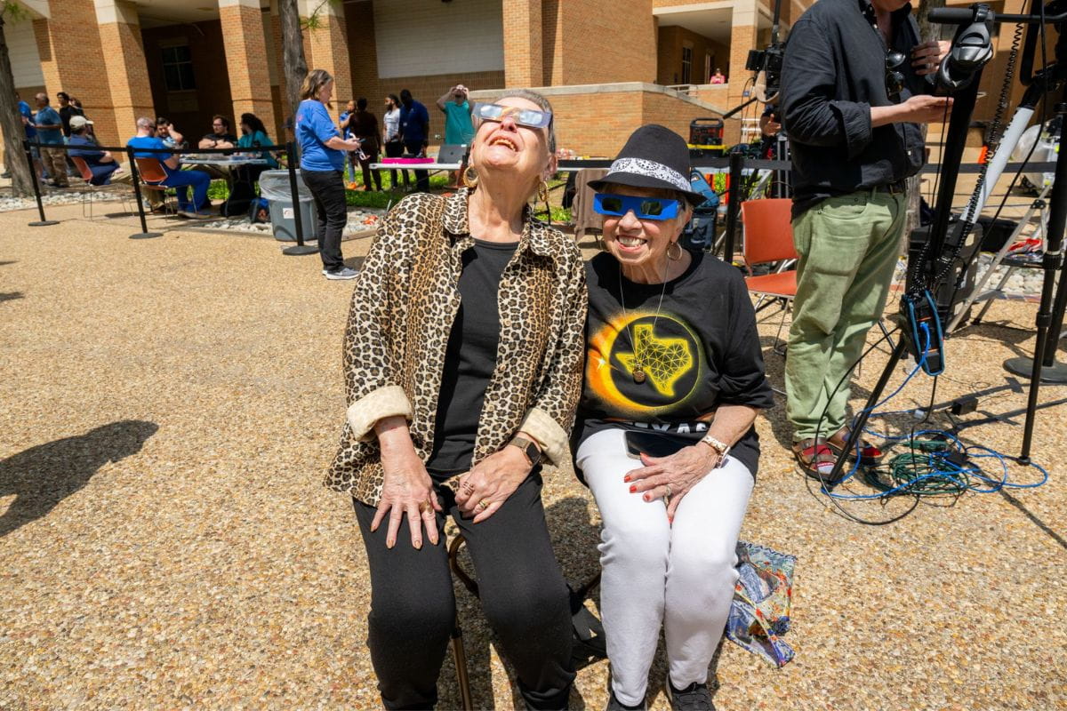 Community members pose for photo with eclipse glasses