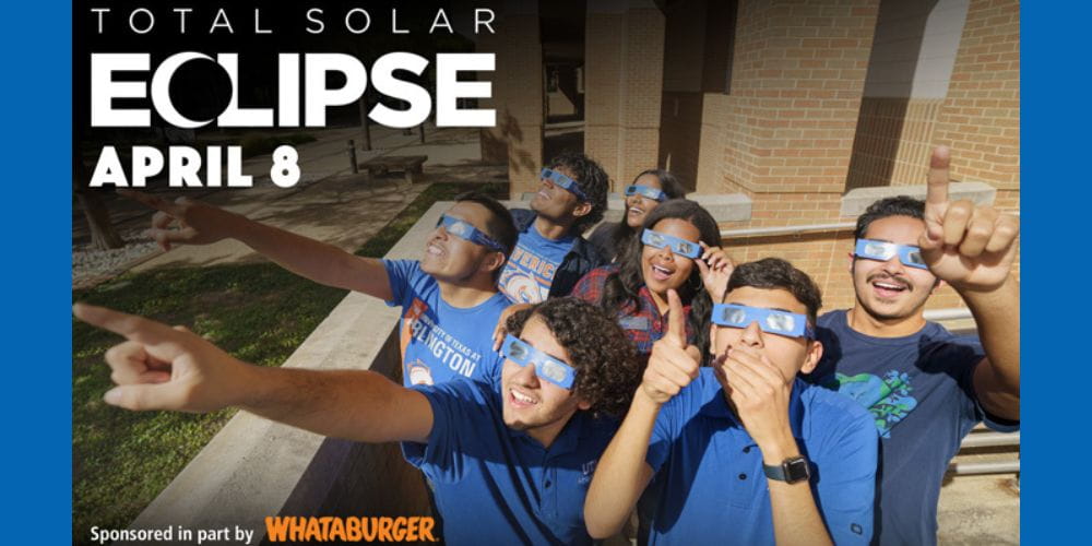 UTA students wearing eclipse glasses look toward the sky