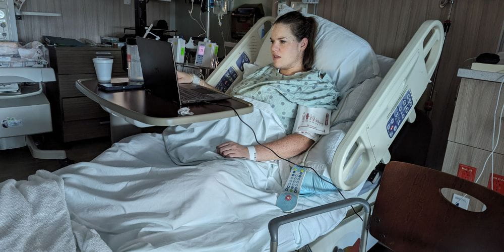 Kelly Meek in hospital bed with laptop open