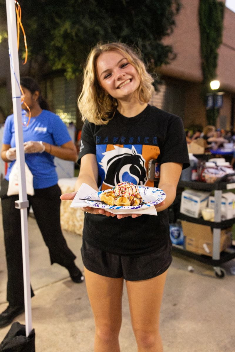 A UTA student holds her waffle with several different toppings