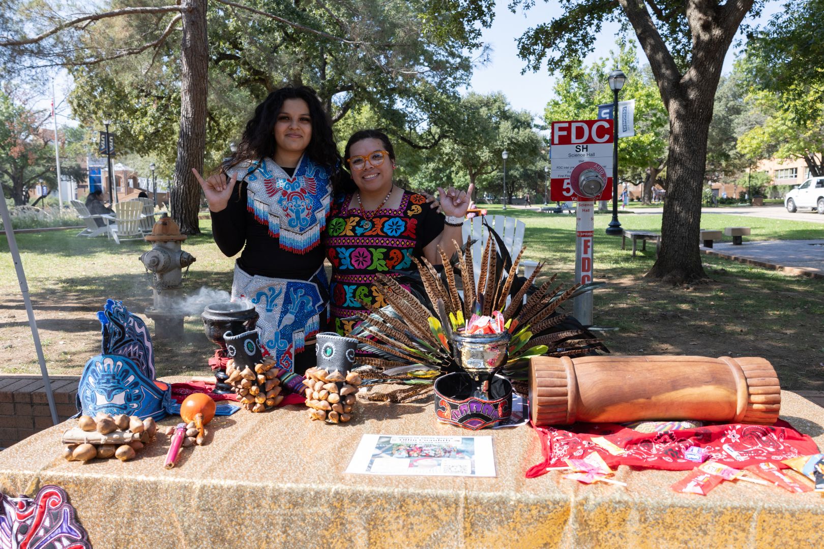 Image shows two UTA students embrace and Mav Up during a Native American heritage tabling event 