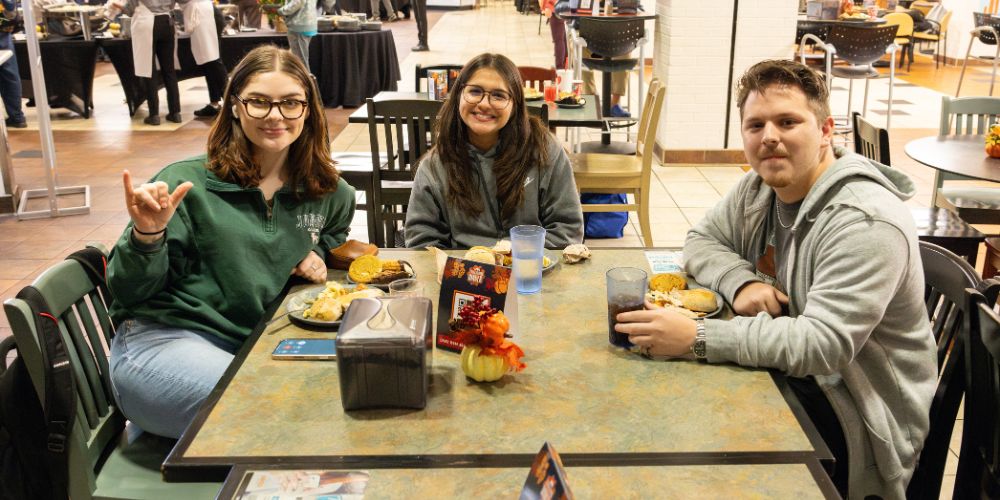 Three students eating dinner at the annual Thanksgiving Dinner