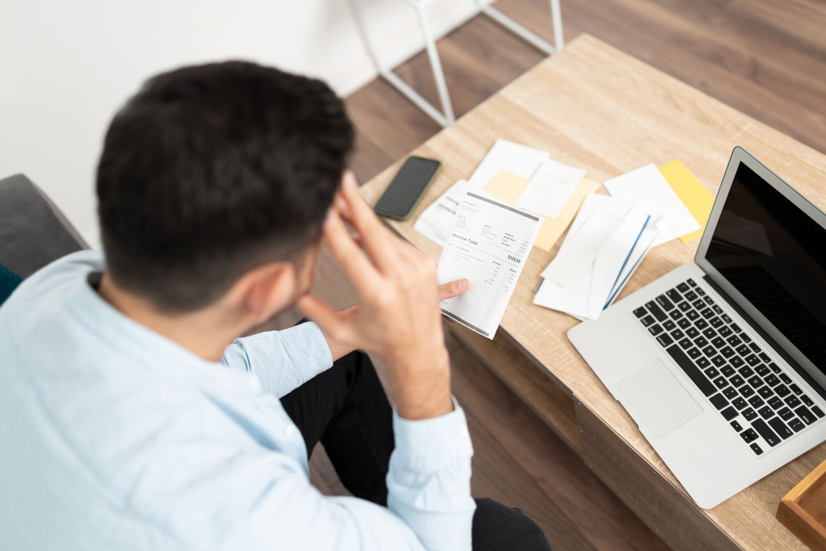 Image shows a stock photo of a person dealing with bills and debt 