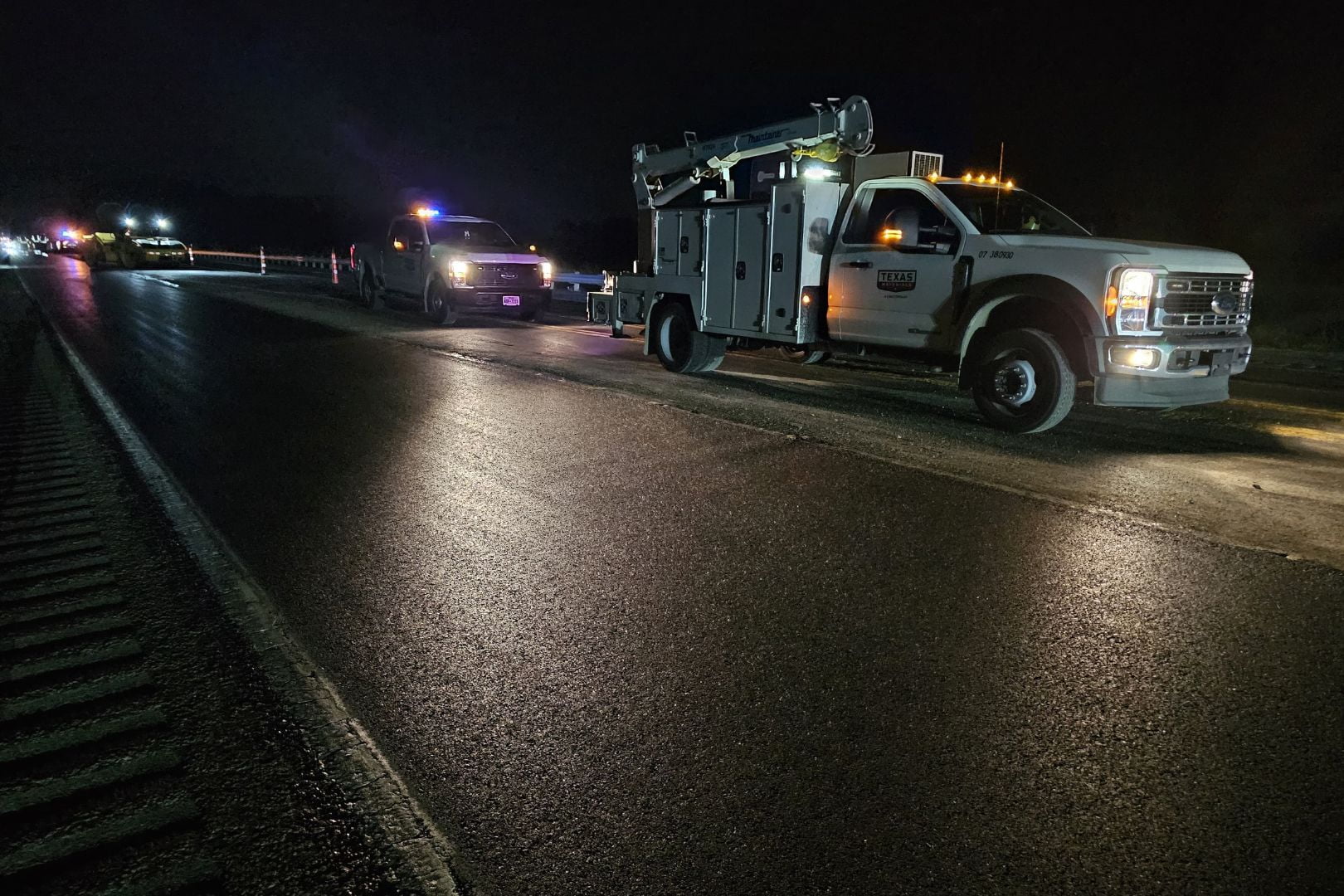 Image shows work trucks parked on the now paved plastic-infused asphalt road
