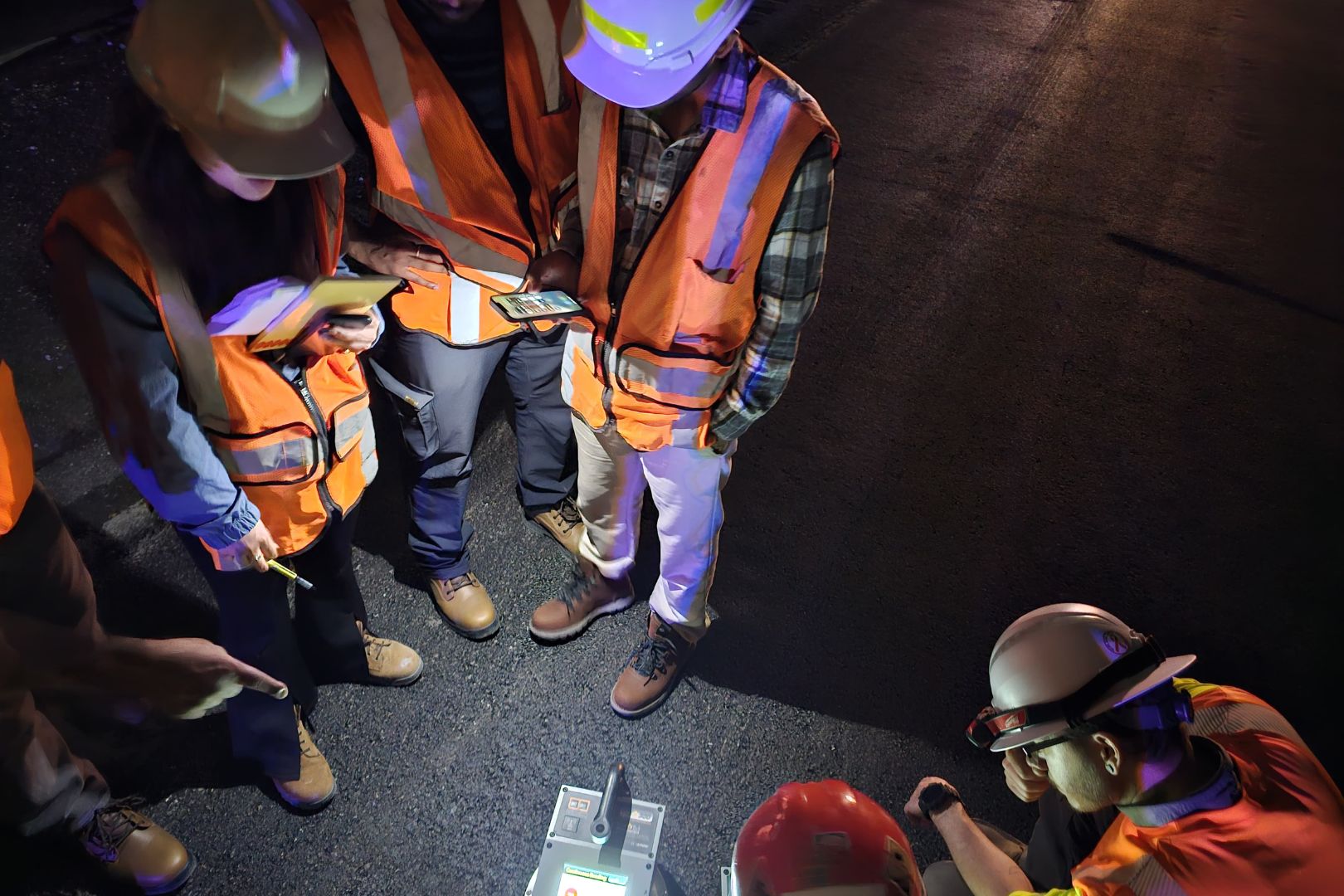 Image shows UTA students and faculty inspecting the plastic-infused asphalt after it was poured 