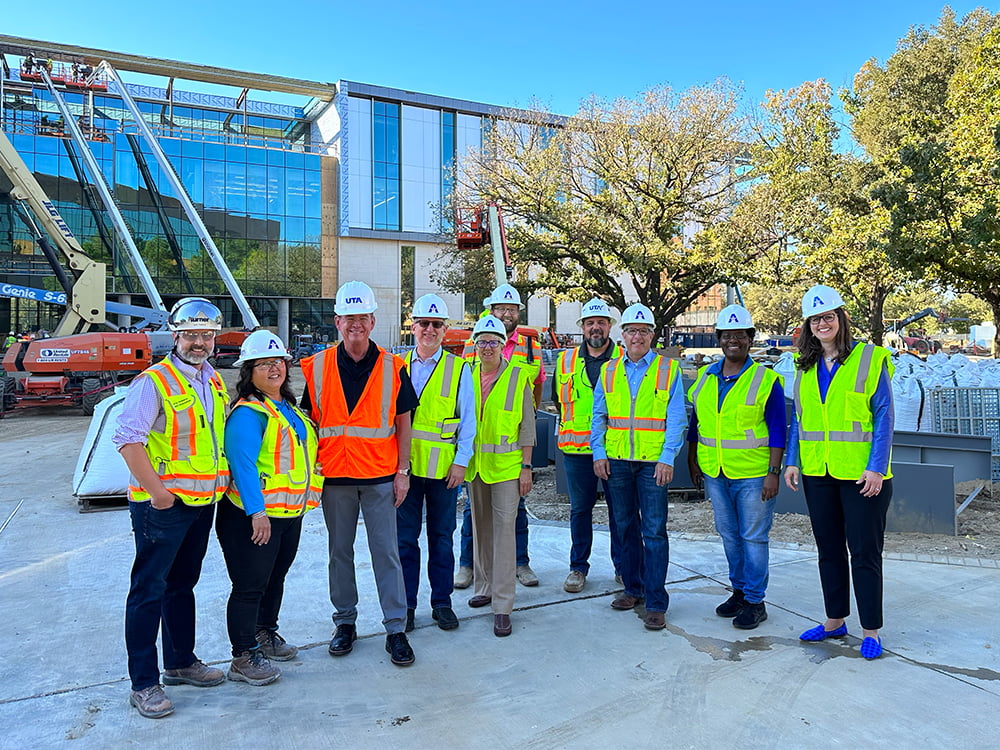 UTA leaders pose in front of the construction of the School of Social Work and Smart Hospital building
