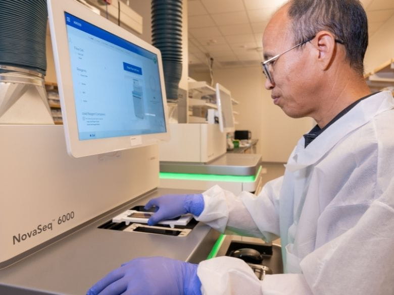 A man places a DNA sample into a sequencing machine.