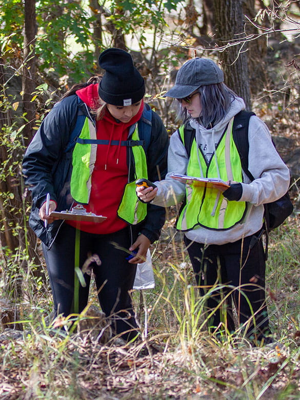 Two students survey a compass at Field Camp.