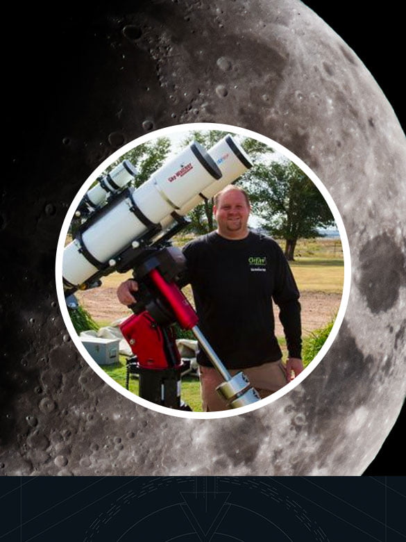 Man posing for a photo behind a huge telescope.