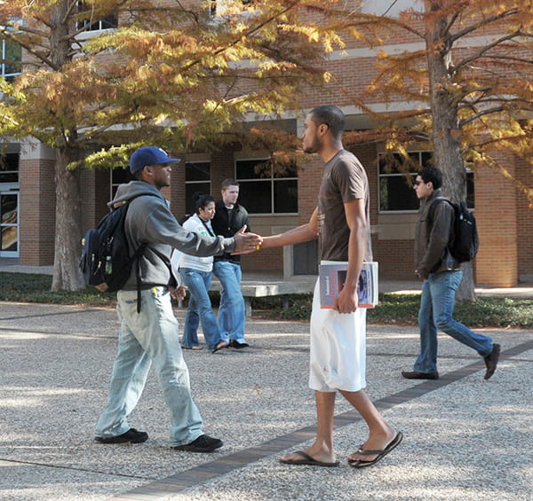Two friends meeting on campus on a sunny fall day outside the Chemistry Research Building.
