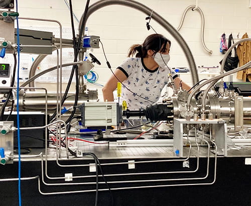 A physics graduate student operating scientific equipment in a laboratory.