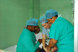 A U.S. Army nurse (center) helps a Dominican staff member (left) while a father holds his daughter following her eye surgery