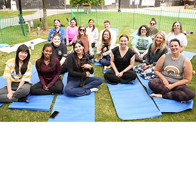 A group of people sitting on yoga mats during the Puppy Yoga event