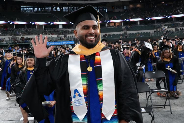 Photo of UTA student holding his hand up during the Fall 2023 Graduation