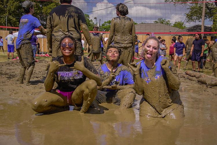 Oozeball contestants sitting in the mud on a hot day