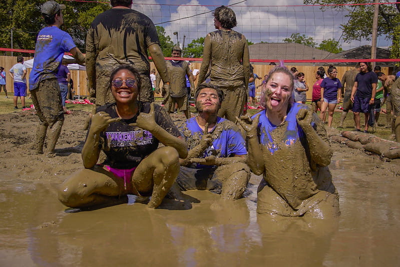 Oozeball contestants sitting in the mud on a hot day